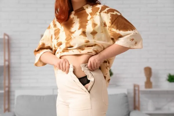 Image of woman trying to do her trousers up after pregnancy weight gain Solihull Lodge